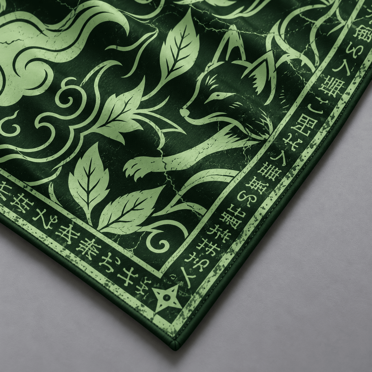 Detalle del zorro y las hojas verde claro sobre fondo verde de la bandana KONOHA de seda.