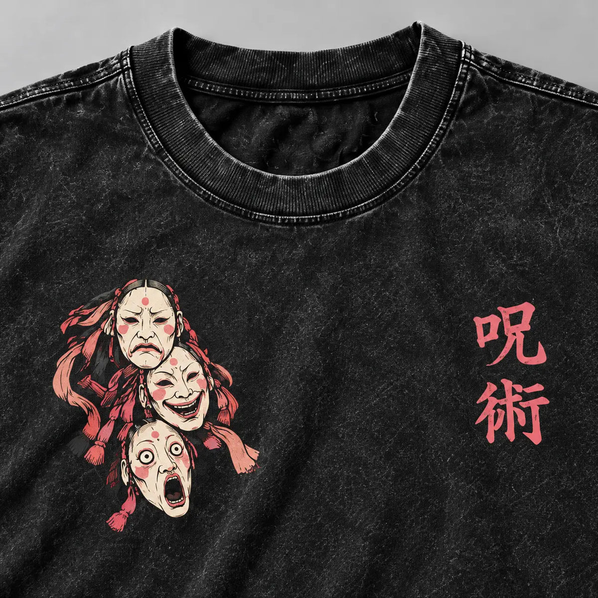 Closeup del cuello en rib, lavado acid wash negro y emblema de tres máscaras en el pecho de la camiseta Tokyo City.